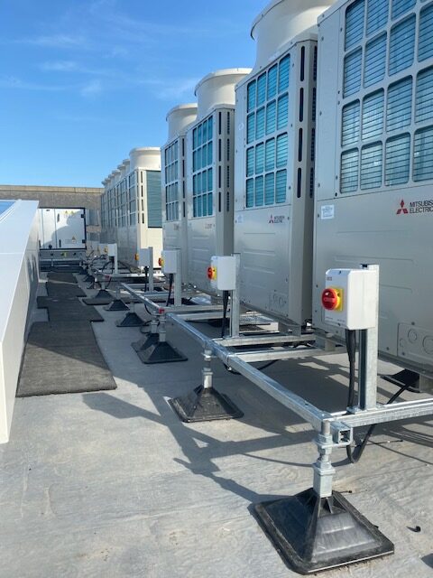 Row of rooftop air-conditioning units with rotary isolators on galvanised frames