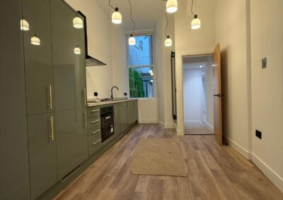 Narrow kitchen with a row of pendant lights and sockets along the wall